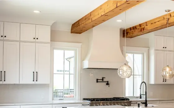 White kitchen with exposed wood ceiling beams and glass pendant lights
